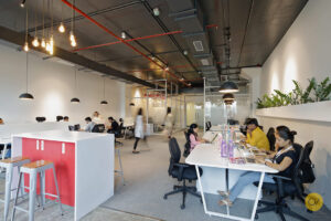 a office design in white and hint of red with grey ceiling and people working